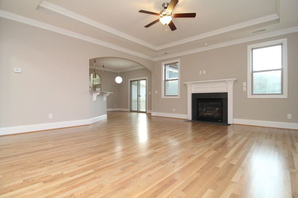 Mid-sized transitional open concept light wood floor living room photo in Raleigh with beige walls, a standard fireplace and a wood fireplace surround