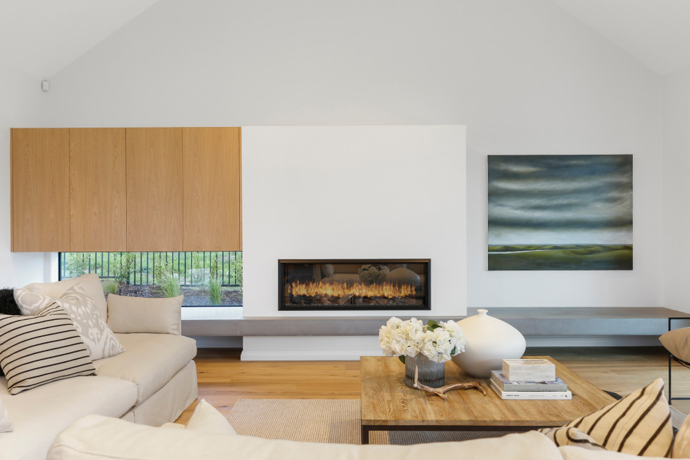 Cette photo montre un salon tendance ouvert avec un mur blanc, un sol en bois brun, une cheminée ribbon, un sol marron et un plafond voûté.