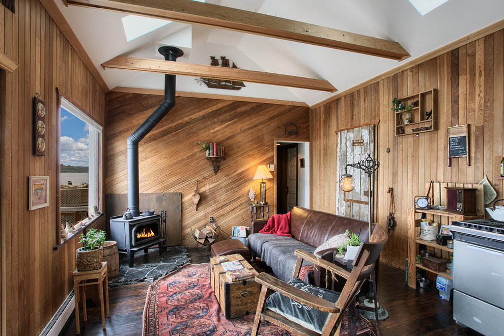 Esempio di un soggiorno rustico con parquet scuro, stufa a legna e tappeto