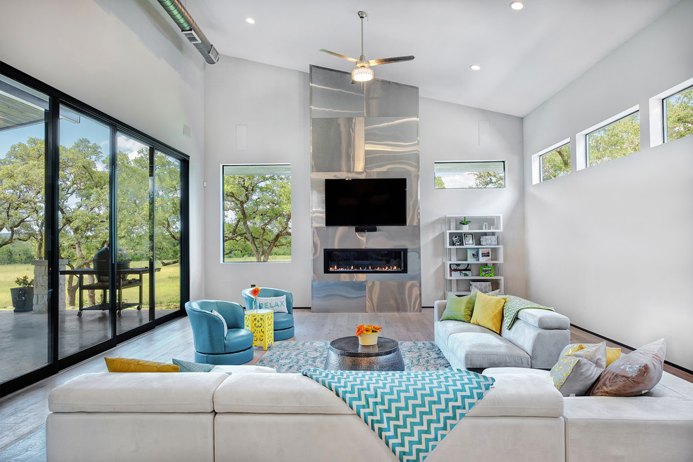 Design ideas for a classic grey and teal living room in Austin with white walls, a ribbon fireplace, a metal fireplace surround, a wall mounted tv and grey floors.