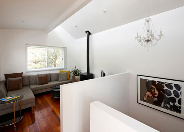 Mittelgroßes Maritimes Wohnzimmer im Loft-Stil mit weißer Wandfarbe, braunem Holzboden, Kaminumrandung aus Metall und freistehendem TV in Melbourne