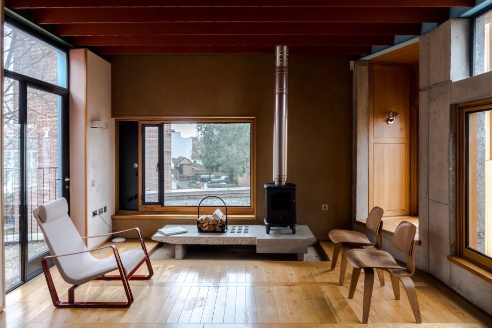 Modelo de salón abierto contemporáneo con paredes marrones, suelo de madera en tonos medios, estufa de leña, suelo marrón y vigas vistas