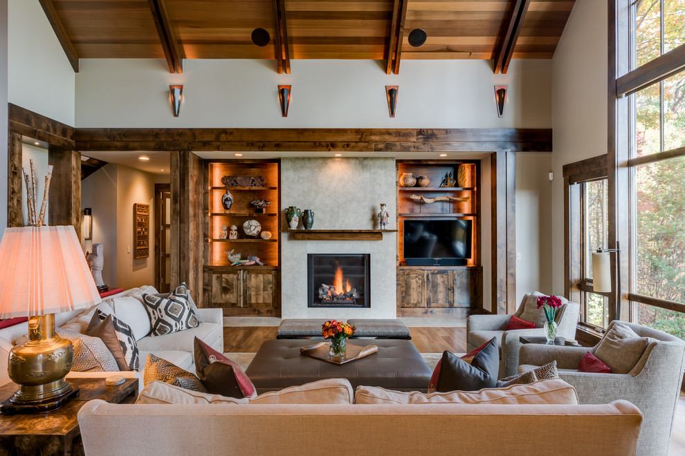 Inspiration pour un grand salon traditionnel ouvert avec un mur beige, un sol en bois brun, une cheminée ribbon, un manteau de cheminée en pierre et un téléviseur encastré.