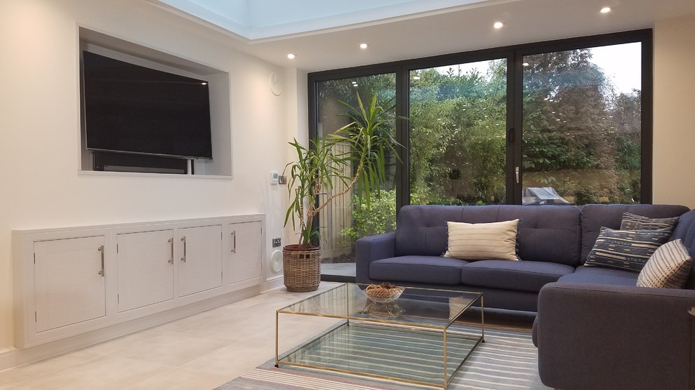 Expansive contemporary open plan living room in Hertfordshire with white walls, porcelain flooring and a wall mounted tv.