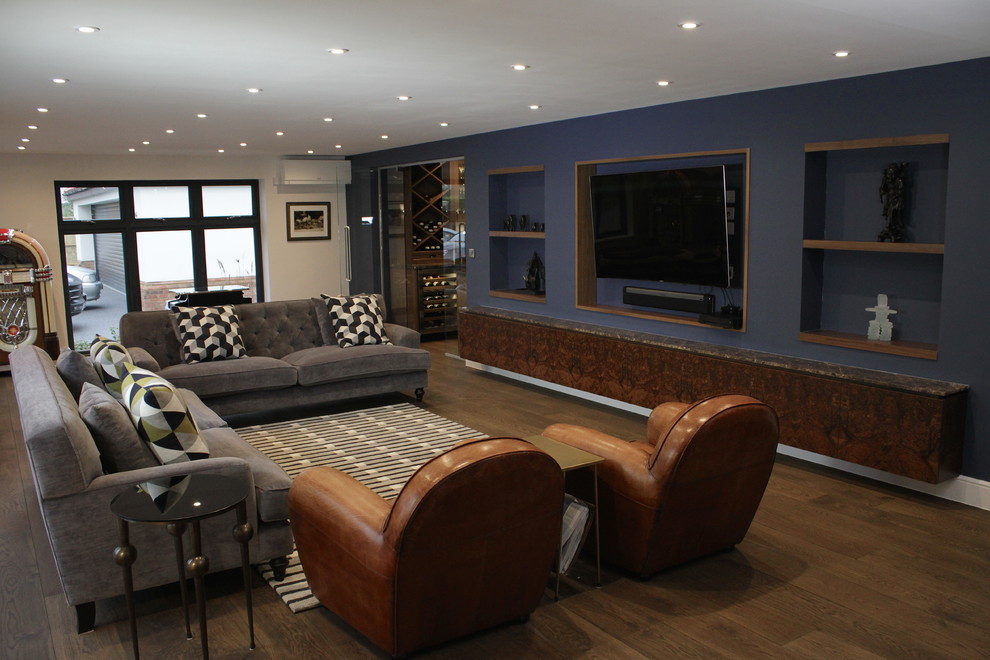 This is an example of a large eclectic open plan living room in London with a home bar, blue walls, dark hardwood flooring and a wall mounted tv.