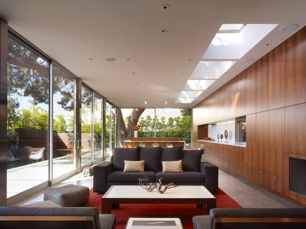 Diseño de salón abierto contemporáneo de tamaño medio con suelo de cemento, paredes blancas, marco de chimenea de madera, televisor retractable y alfombra