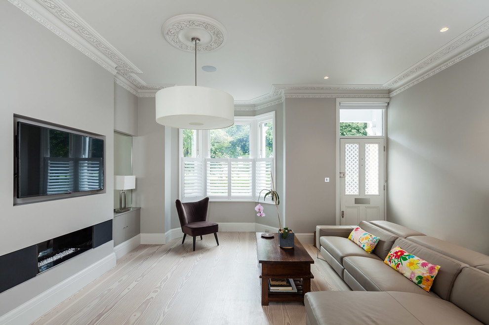 Immagine di un soggiorno minimal di medie dimensioni con sala formale, pareti grigie, parquet chiaro, camino lineare Ribbon e TV a parete