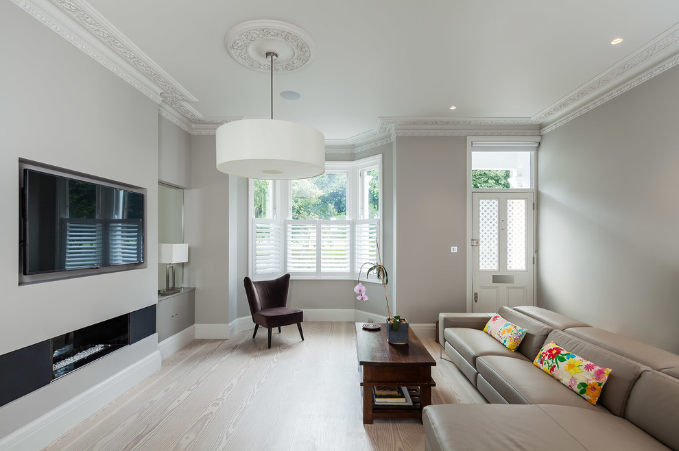 Example of a mid-sized trendy formal light wood floor living room design in London with gray walls, a ribbon fireplace and a wall-mounted tv