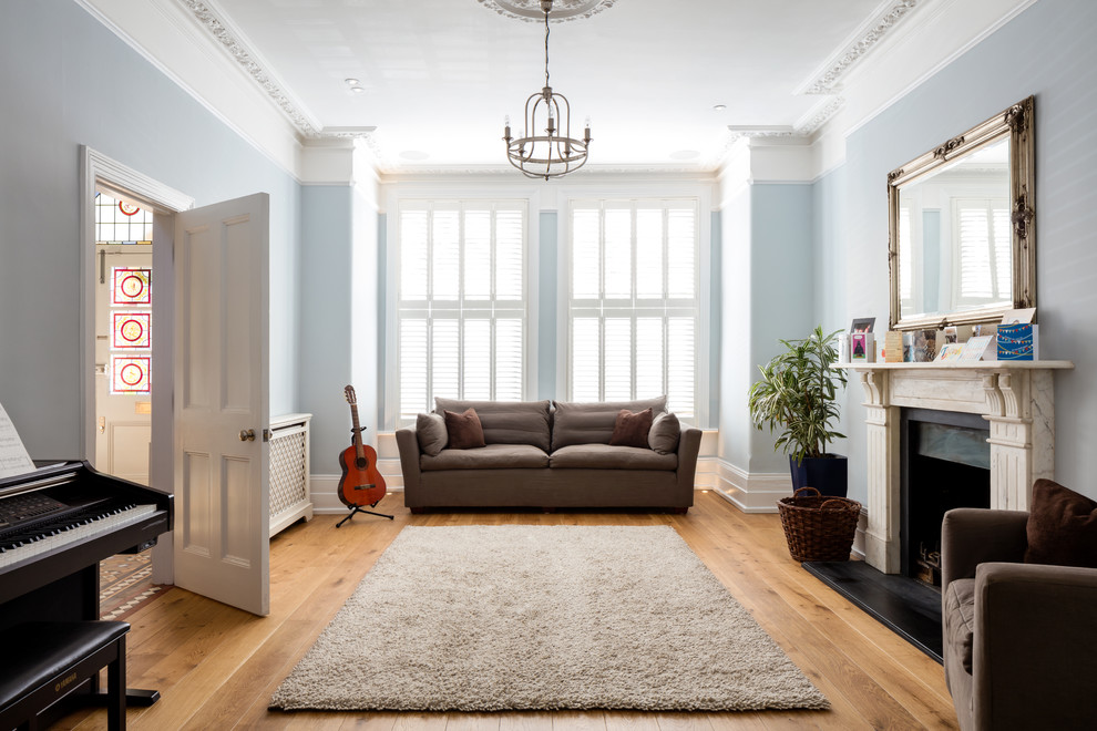 Inspiration för ett stort vintage separat vardagsrum, med ett musikrum, blå väggar, mellanmörkt trägolv, en standard öppen spis, en spiselkrans i sten och brunt golv