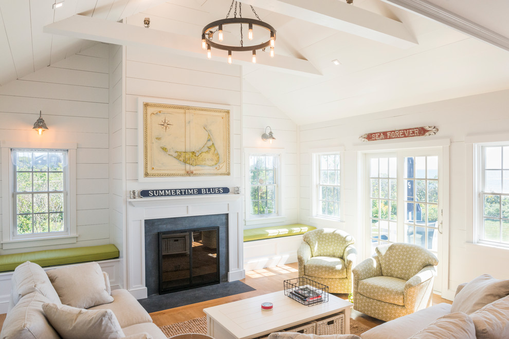 Medium sized beach style formal enclosed living room in Boston with white walls, medium hardwood flooring, a standard fireplace, no tv, a wooden fireplace surround and brown floors.