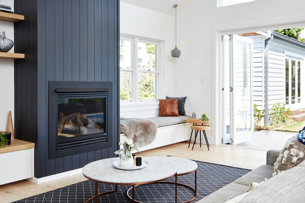 Idee per un soggiorno design aperto con pareti bianche, parquet chiaro, stufa a legna e cornice del camino in legno