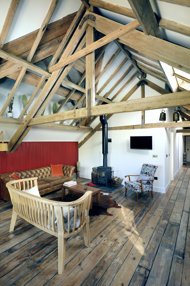 Modelo de salón de estilo de casa de campo con paredes blancas, suelo de madera en tonos medios y estufa de leña