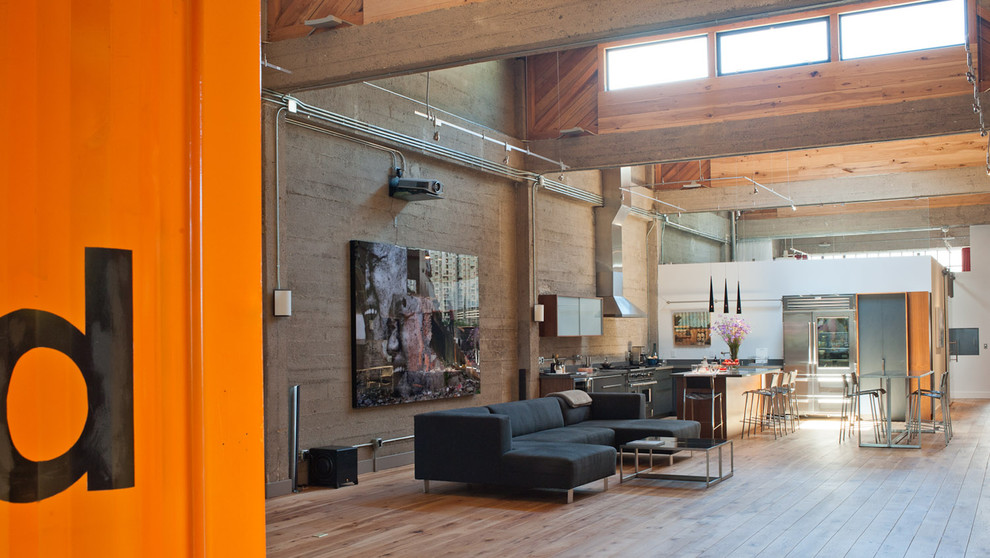Imagen de salón para visitas abierto industrial grande sin chimenea y televisor con suelo de madera en tonos medios, paredes grises y suelo marrón