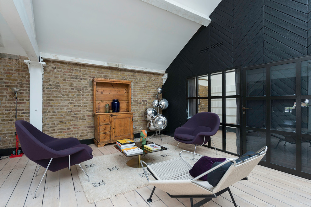 Пример оригинального дизайна: гостиная комната в стиле лофт с черными стенами и деревянным полом без камина, телевизора