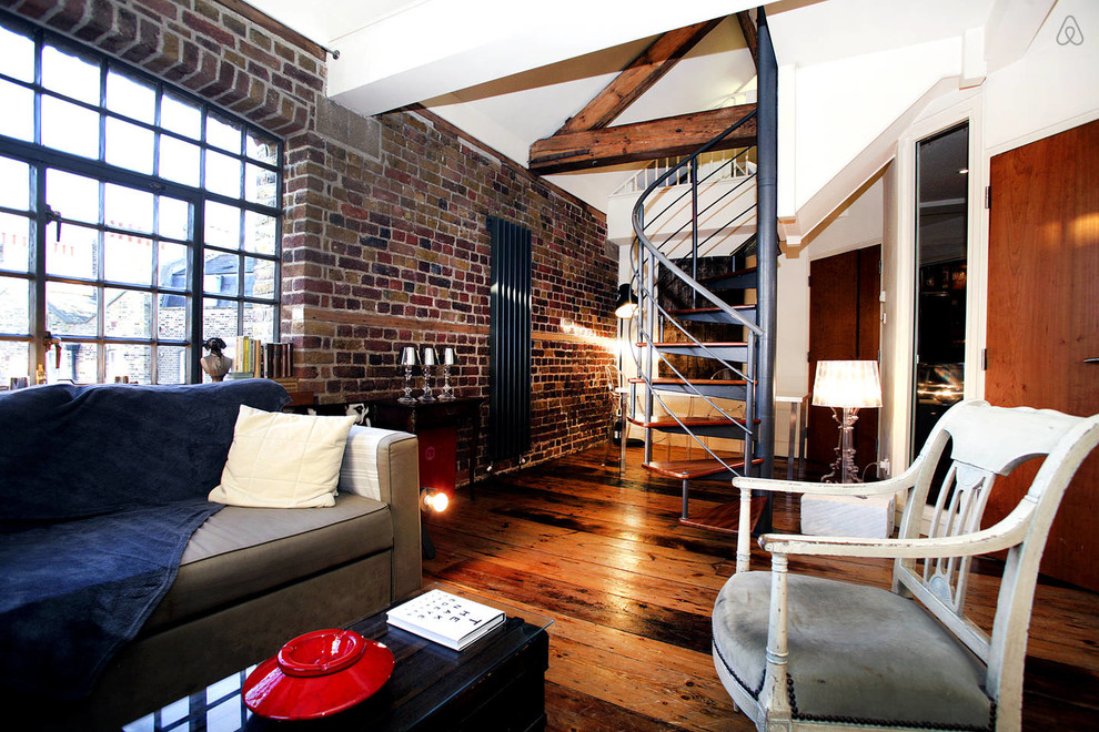 This is an example of an industrial open plan living room in London with dark hardwood flooring.