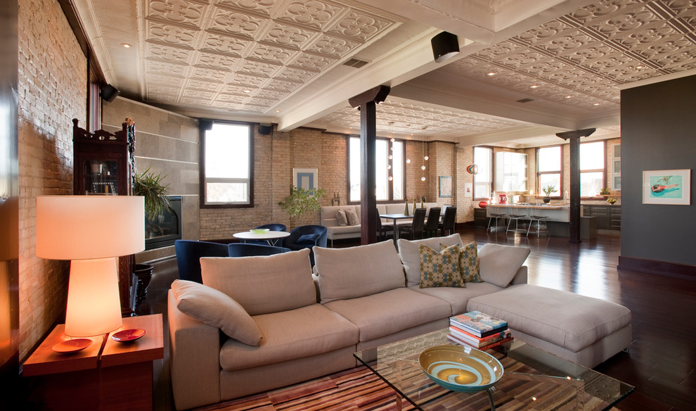 Ejemplo de salón tipo loft actual extra grande con suelo de madera en tonos medios, chimenea de esquina y marco de chimenea de piedra