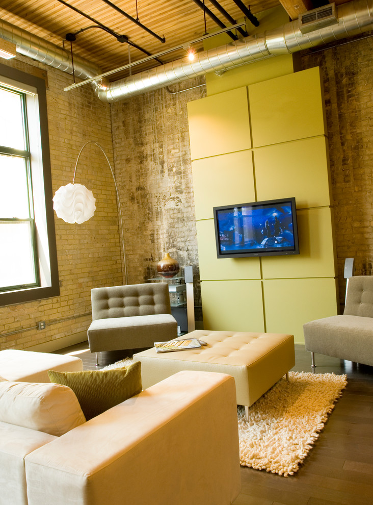 Cette photo montre un salon mansardé ou avec mezzanine tendance avec un mur jaune, un sol en bois brun et un téléviseur fixé au mur.