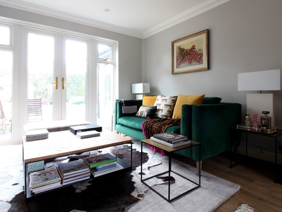 Design ideas for a medium sized eclectic formal enclosed living room in Surrey with grey walls, laminate floors, a standard fireplace, a concrete fireplace surround, a freestanding tv and brown floors.