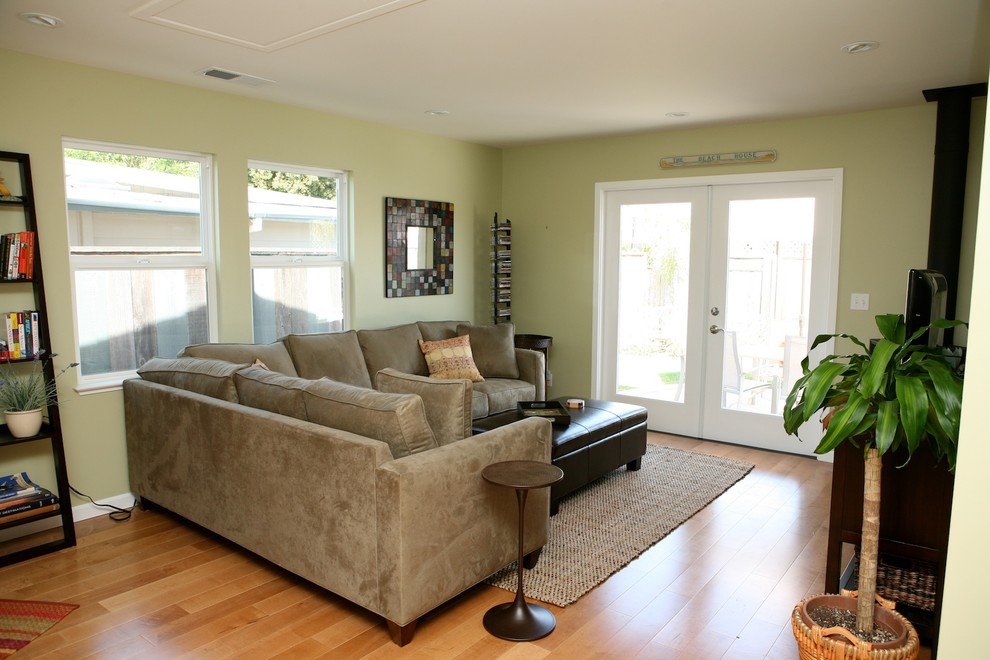 Mittelgroßes, Offenes Modernes Wohnzimmer mit grüner Wandfarbe, braunem Holzboden, Kaminofen und freistehendem TV in Sonstige