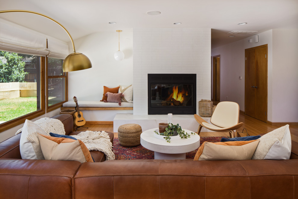 This is an example of a medium sized scandi formal open plan living room in Los Angeles with white walls, bamboo flooring, a standard fireplace, a tiled fireplace surround, no tv and yellow floors.