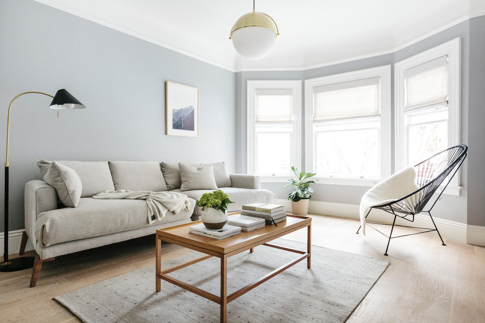This is an example of a scandinavian living room in San Francisco with grey walls and light hardwood flooring.