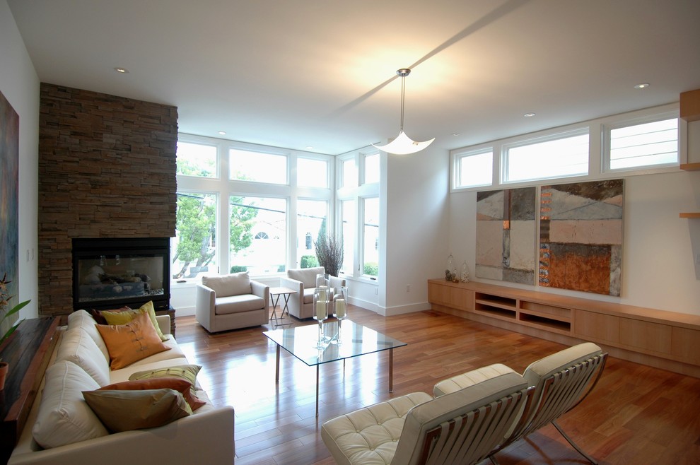 Diseño de salón abierto moderno grande con paredes blancas y suelo de madera en tonos medios