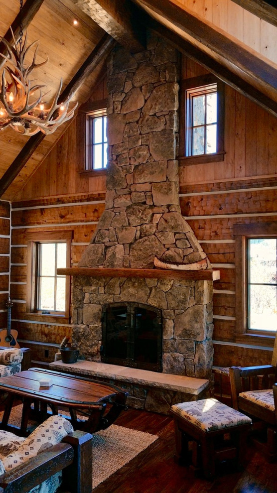 Diseño de salón tipo loft rústico pequeño sin televisor con paredes marrones, suelo de madera oscura, todas las chimeneas y marco de chimenea de piedra