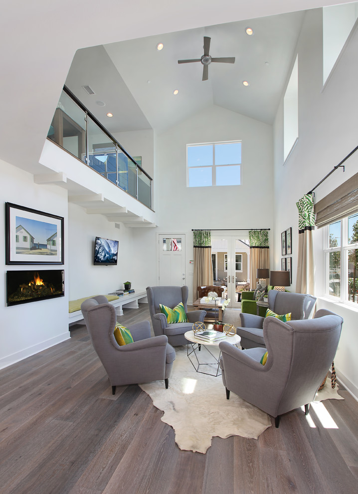 Classic open plan living room in Orange County with white walls, a ribbon fireplace, a wall mounted tv and grey floors.