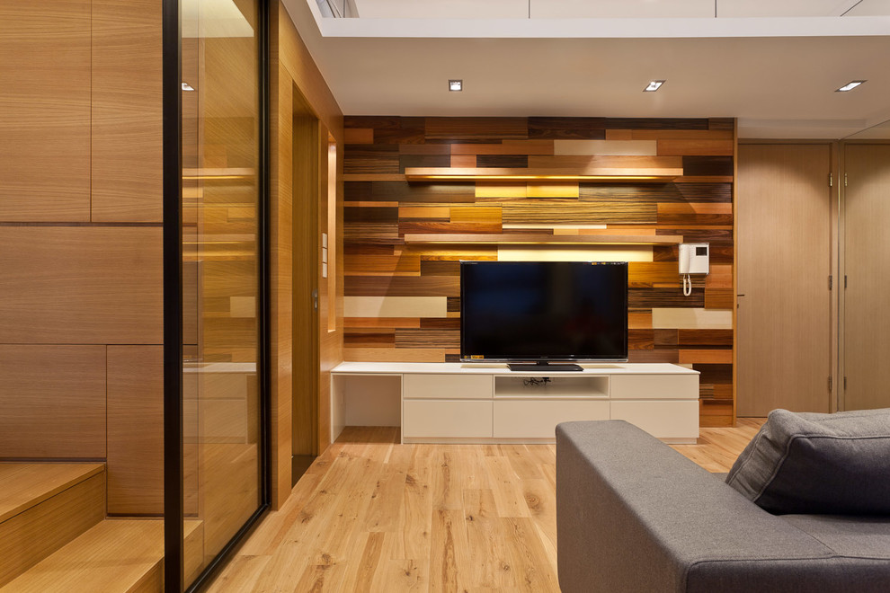 Diseño de salón abierto actual pequeño sin chimenea con paredes blancas, suelo de madera clara y televisor colgado en la pared
