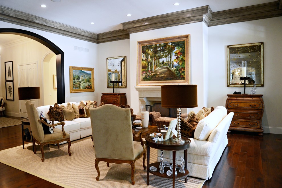 Modelo de salón para visitas clásico sin televisor con paredes blancas, suelo de madera en tonos medios, todas las chimeneas y marco de chimenea de piedra