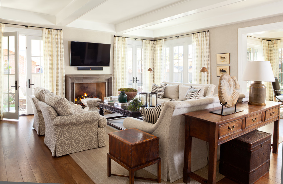Aménagement d'un grand salon classique ouvert avec une salle de réception, un mur beige, un sol en bois brun, une cheminée standard et un manteau de cheminée en pierre.
