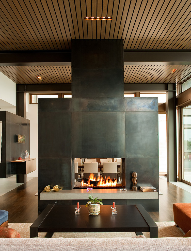 This is an example of a contemporary formal open plan living room in Seattle with dark hardwood flooring, a two-sided fireplace and no tv.