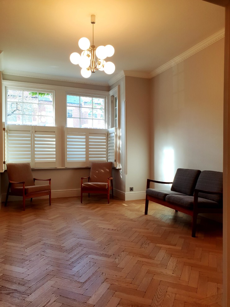 Imagen de salón para visitas abierto, clásico, extra grande, con paredes beige, suelo de madera en tonos medios, todas las chimeneas, marco de chimenea de metal, televisor independiente, suelo marrón y bandeja