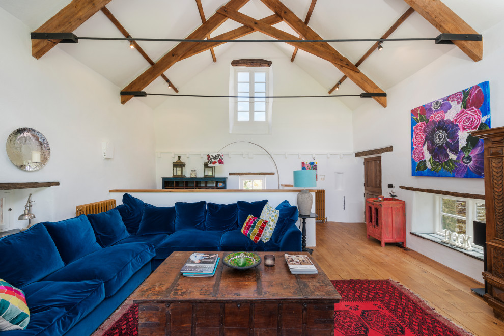 Großes Landhaus Wohnzimmer mit weißer Wandfarbe, braunem Holzboden, braunem Boden, freigelegten Dachbalken und gewölbter Decke in Devon
