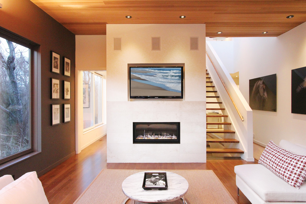 Foto de salón abierto contemporáneo de tamaño medio con paredes blancas, suelo de madera en tonos medios, chimenea lineal, marco de chimenea de yeso y televisor colgado en la pared