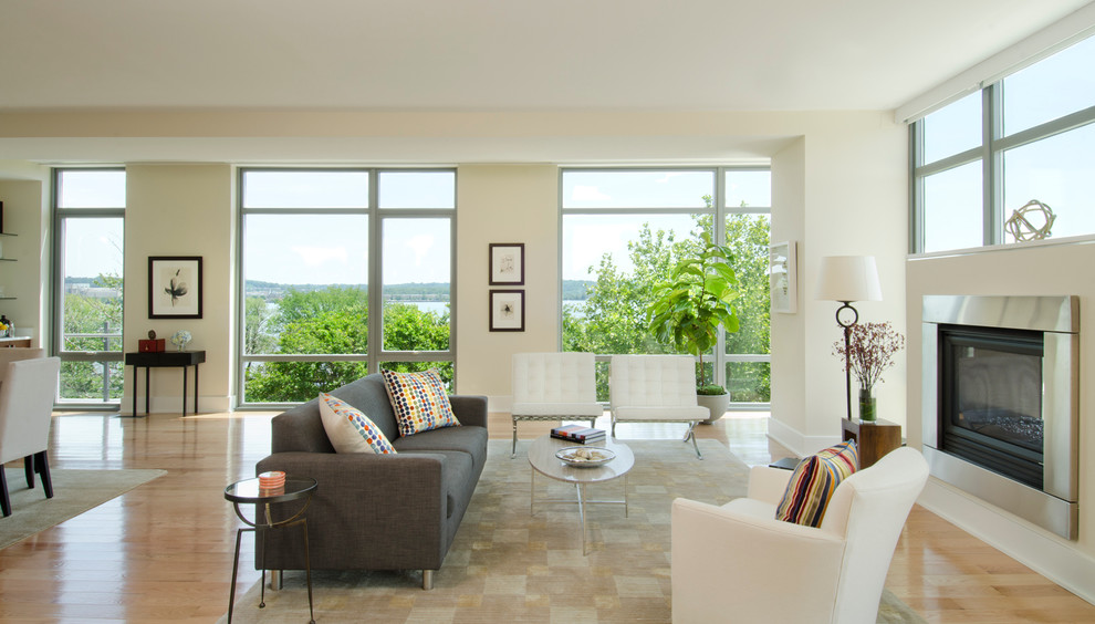 Immagine di un soggiorno design aperto con pareti bianche, pavimento in legno massello medio, camino classico e cornice del camino in metallo