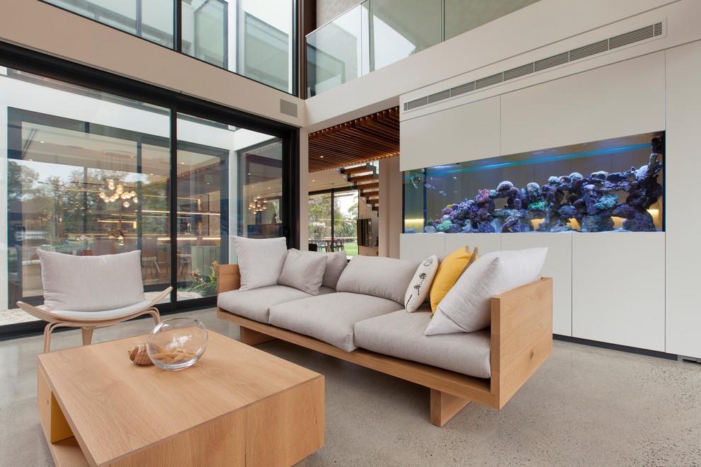 Пример оригинального дизайна: гостиная комната в современном стиле с бетонным полом и телевизором на стене