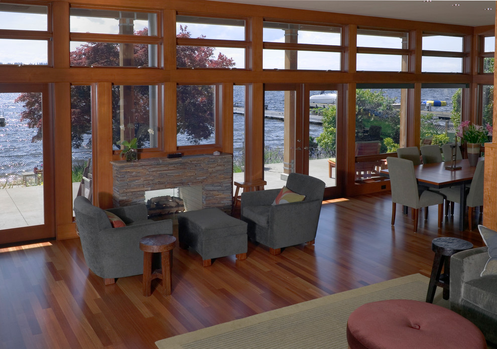 Contemporary open plan living room in Seattle with medium hardwood flooring, a two-sided fireplace, a stone fireplace surround, no tv and beige walls.