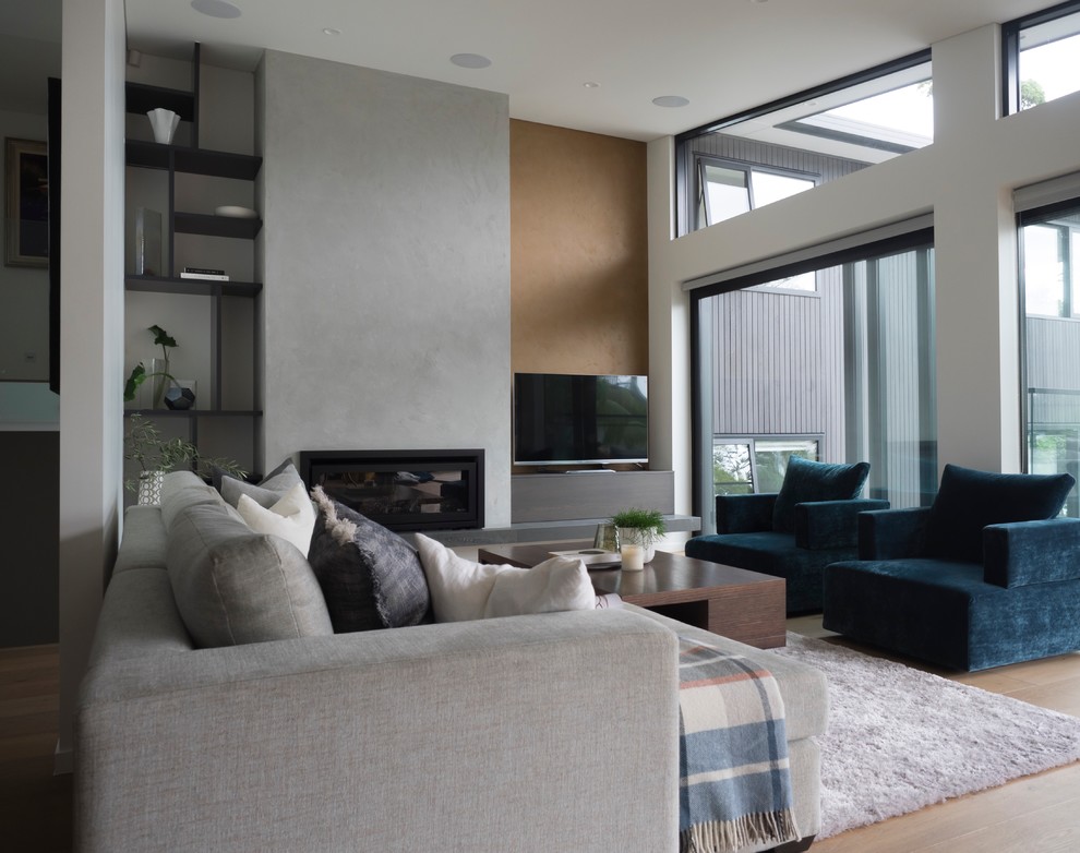 Источник вдохновения для домашнего уюта: гостиная комната в современном стиле с стандартным камином, фасадом камина из бетона, бежевым полом, белыми стенами, светлым паркетным полом и телевизором на стене