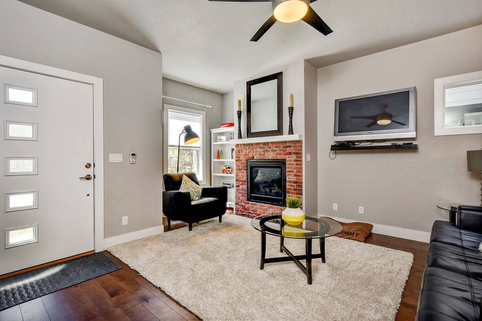 Kleines, Offenes Modernes Wohnzimmer mit grauer Wandfarbe, braunem Holzboden, Kamin, Kaminumrandung aus Backstein und TV-Wand in Boise