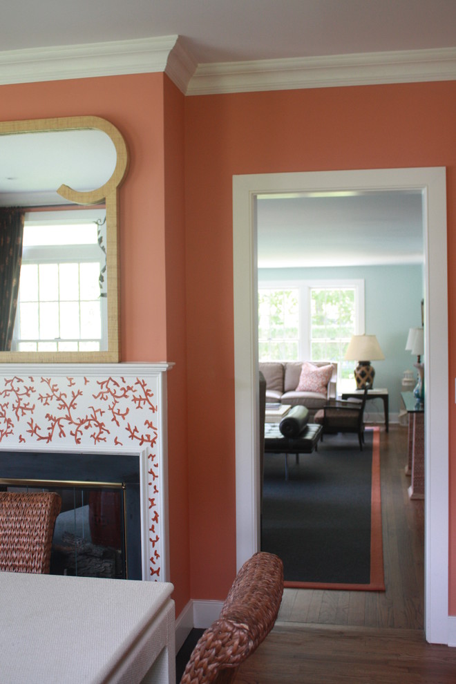 На фото: изолированная гостиная комната среднего размера в стиле фьюжн с оранжевыми стенами, темным паркетным полом, стандартным камином и фасадом камина из штукатурки с