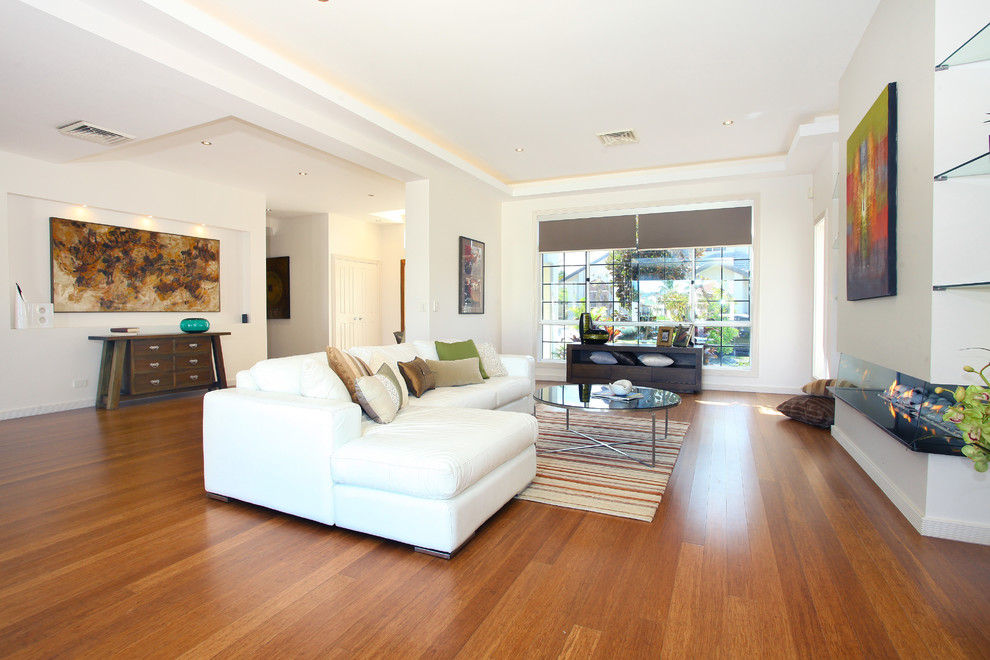 Стильный дизайн: большая открытая гостиная комната в морском стиле с белыми стенами, полом из бамбука и горизонтальным камином без телевизора - последний тренд