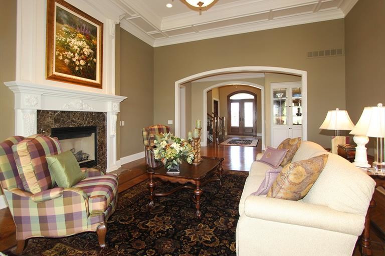 Exemple d'un grand salon chic ouvert avec une salle de réception, un mur beige, un sol en bois brun, une cheminée standard, un manteau de cheminée en pierre et aucun téléviseur.