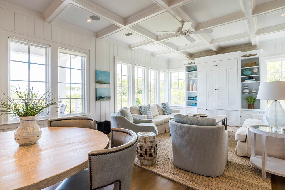 Idee per un ampio soggiorno stile marino aperto con pareti bianche, pavimento marrone, pavimento in legno massello medio e TV nascosta