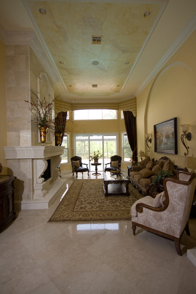 Immagine di un soggiorno tropicale aperto con pareti gialle, pavimento in marmo, camino classico, cornice del camino in intonaco e pavimento beige