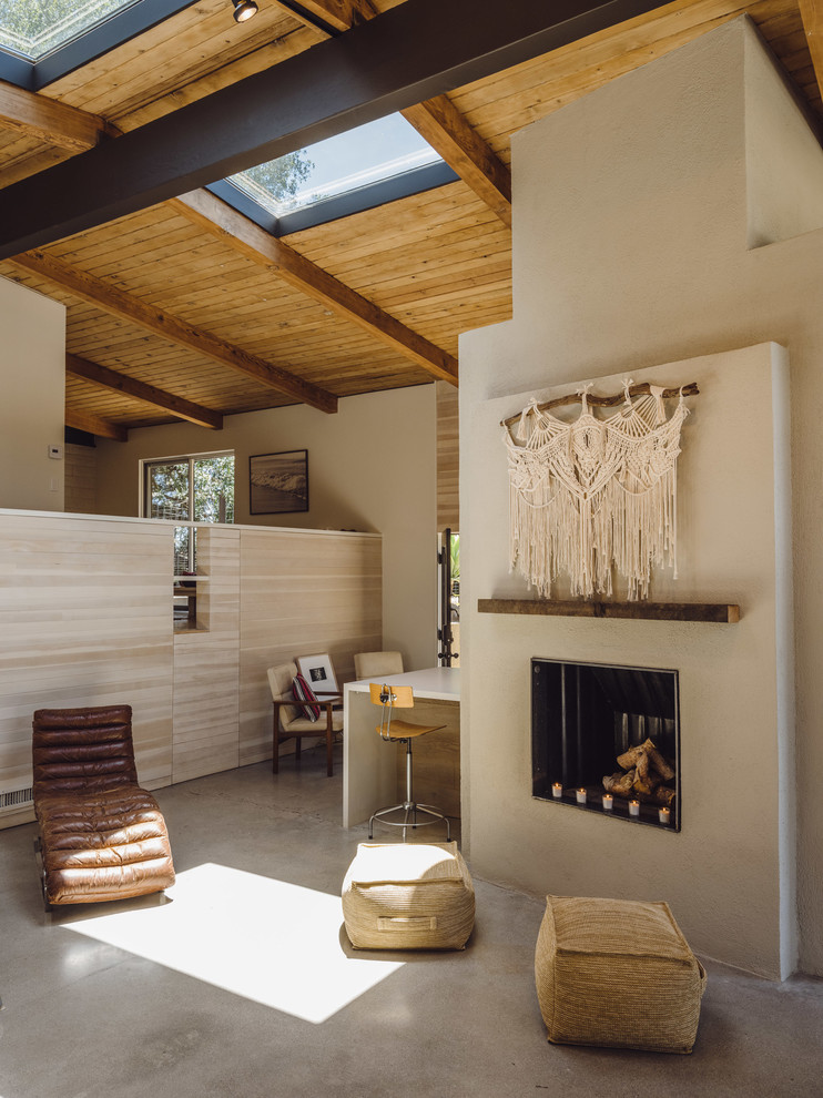 This is an example of a medium sized contemporary open plan living room in Los Angeles with white walls, concrete flooring, a standard fireplace, a plastered fireplace surround, no tv and grey floors.