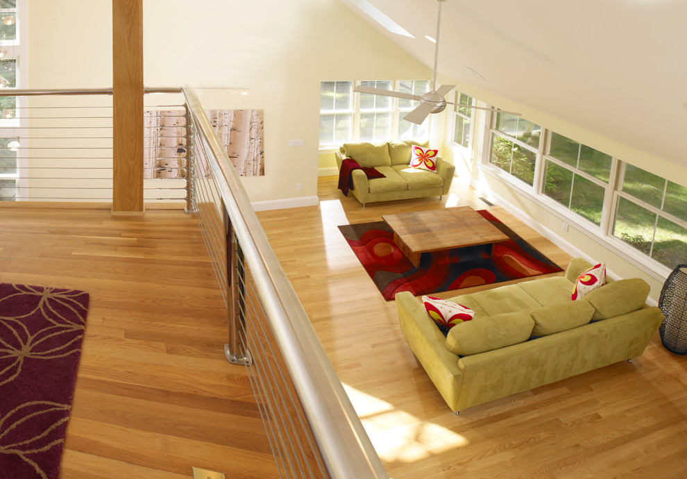 Modelo de salón para visitas tipo loft contemporáneo de tamaño medio sin chimenea y televisor con paredes amarillas y suelo de madera clara