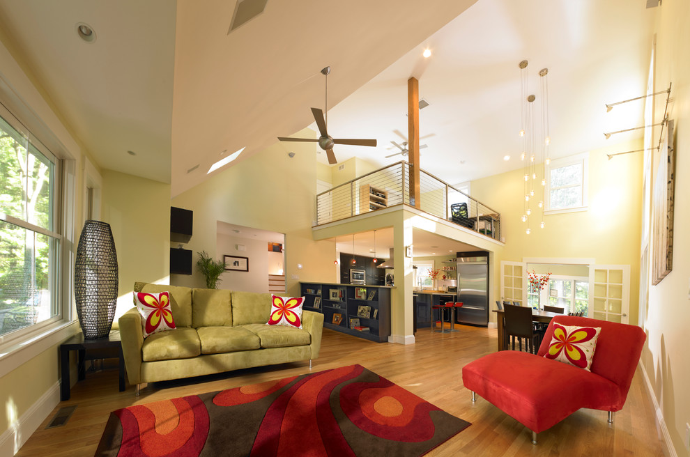 Modelo de salón para visitas tipo loft contemporáneo de tamaño medio sin chimenea y televisor con paredes amarillas y suelo de madera clara