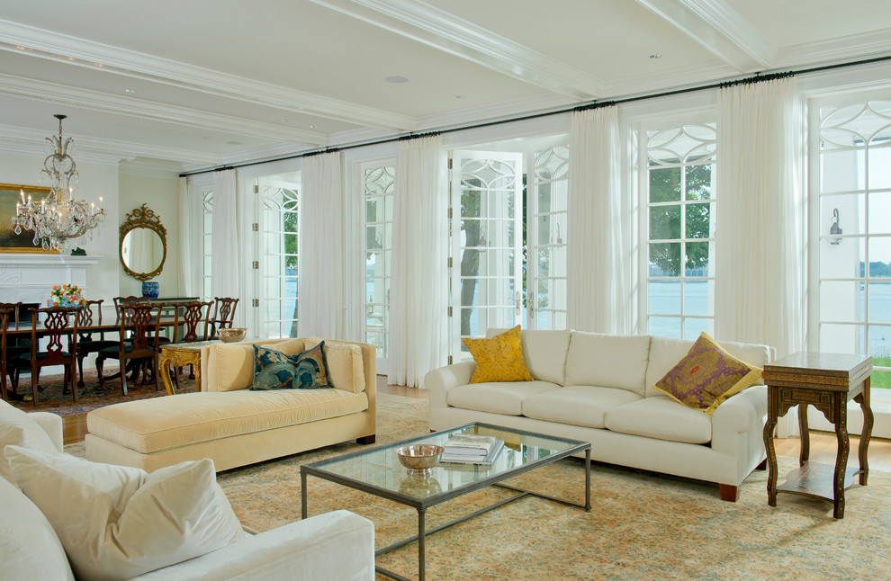 На фото: парадная, открытая гостиная комната в классическом стиле с белыми стенами, светлым паркетным полом и стандартным камином с