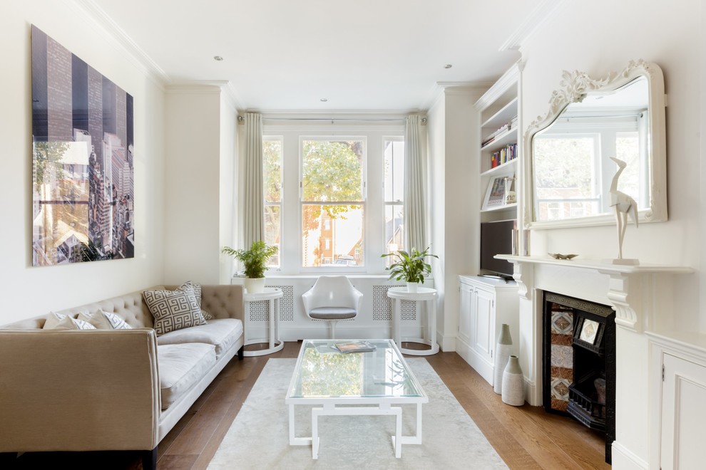 Abgetrenntes Klassisches Wohnzimmer mit beiger Wandfarbe, braunem Holzboden, Kamin, freistehendem TV und braunem Boden in London